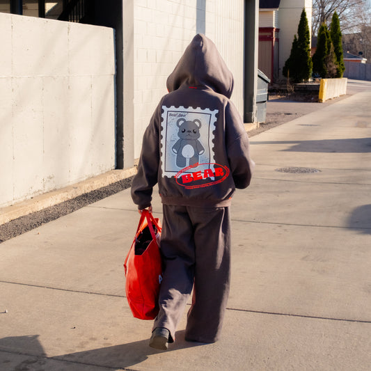 Person wearing a hoodie with a graphic design, walking on a sidewalk.