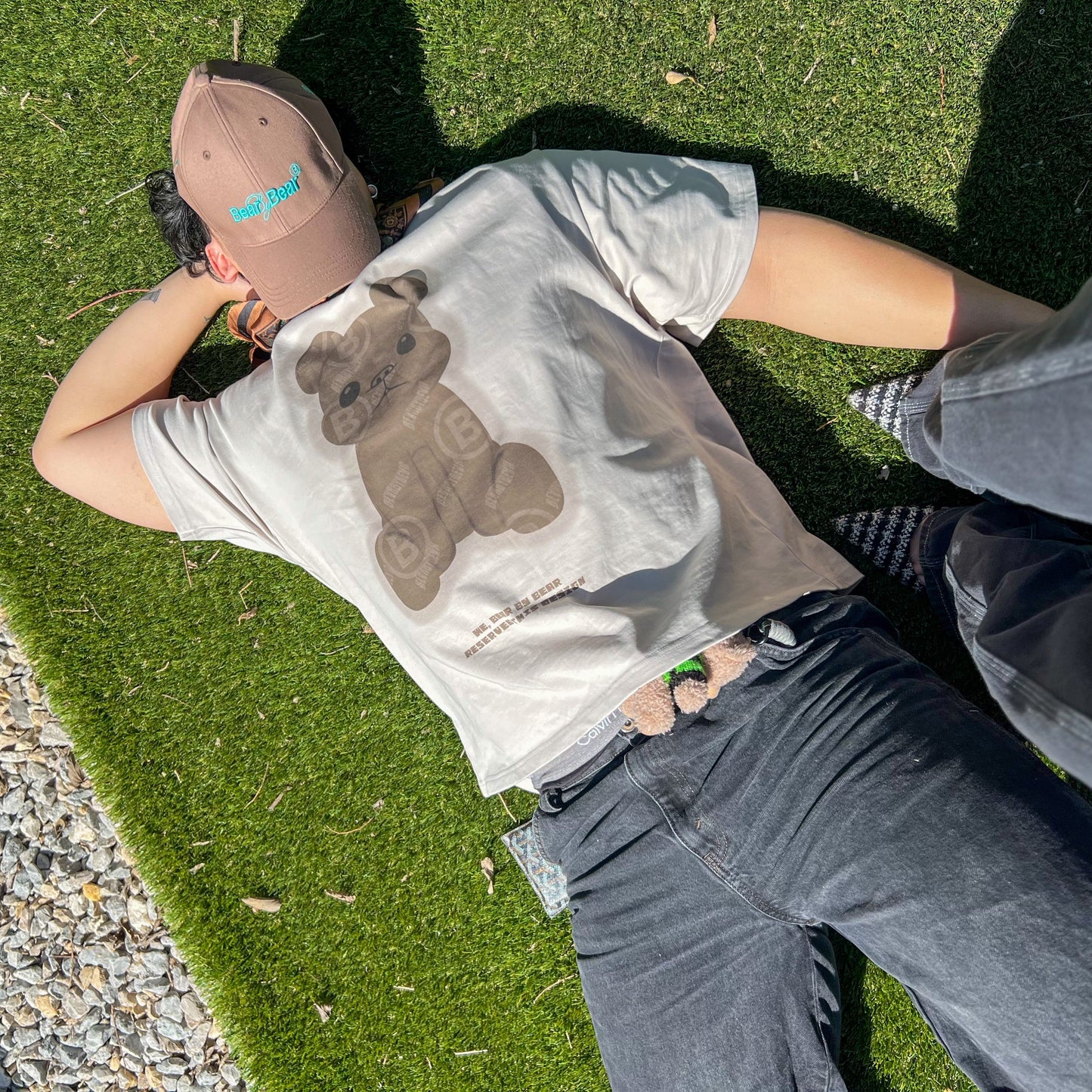 Person lying on grass wearing a t-shirt with a koala design
