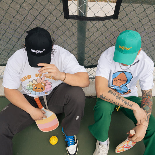 Two people sitting on a basketball court with colorful shoes and graphic t-shirts.